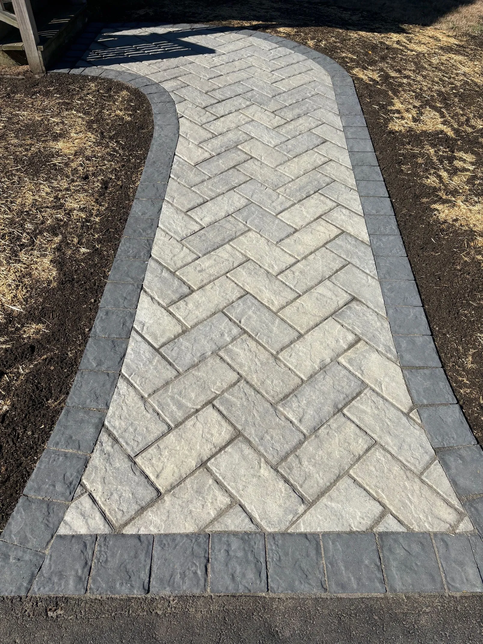 Finished herringbone paver walkway with a charcoal border